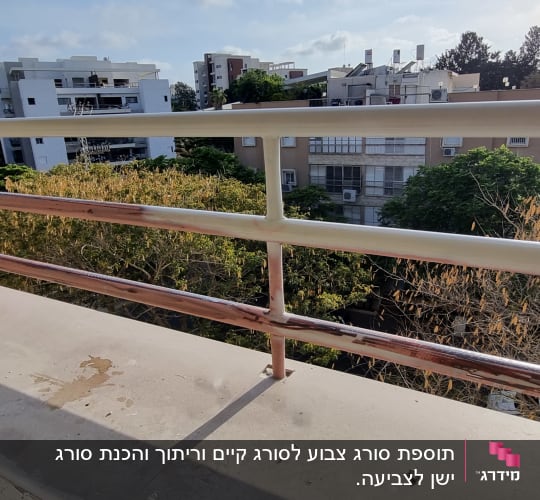 מעקה מתכת במרפסת עם נוף של בניינים ועצים